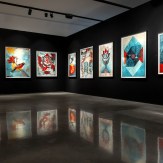 A modern art gallery with a black wall displaying seven framed art prints. The prints feature colorful designs, birds…