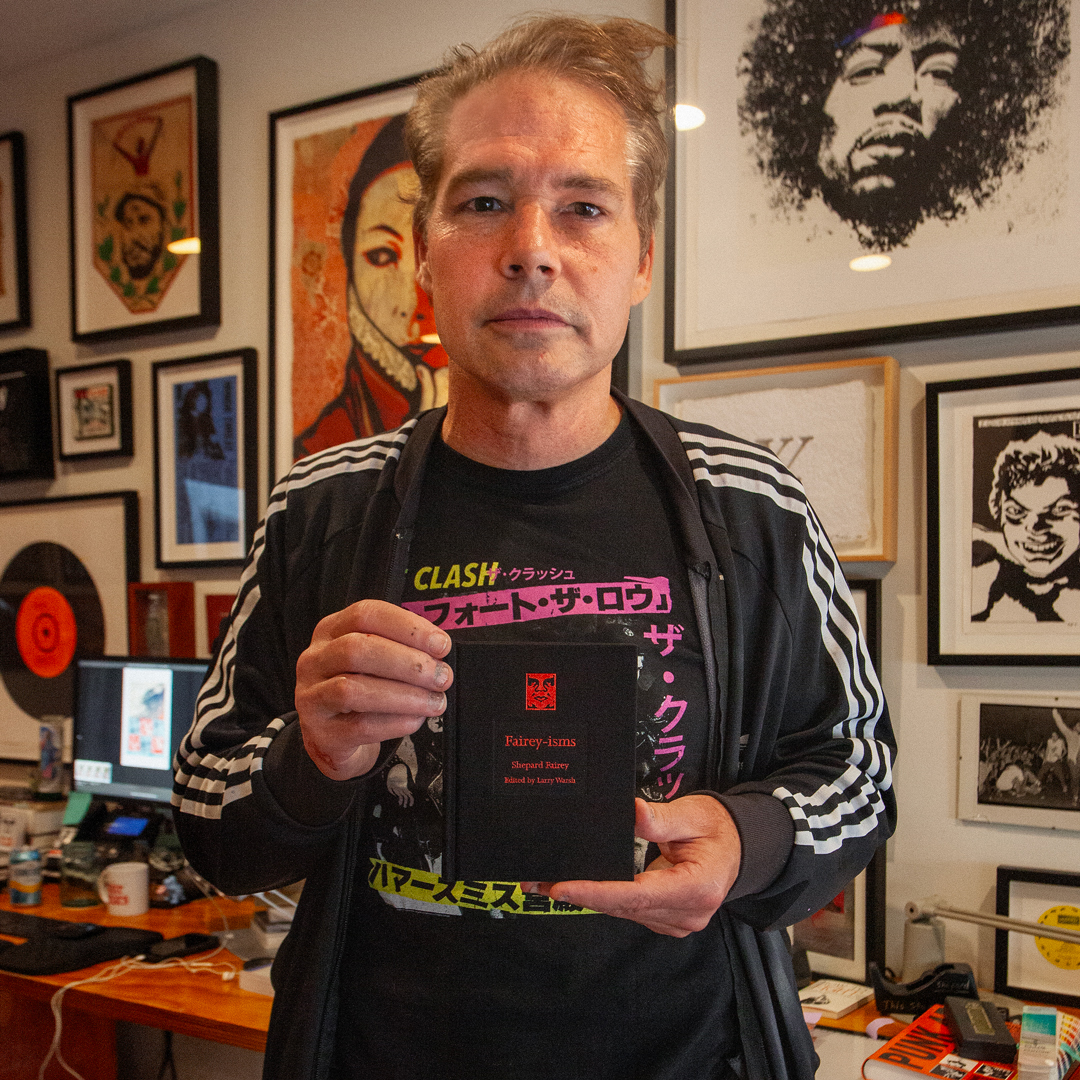 A man in a black jacket holding a black book titled