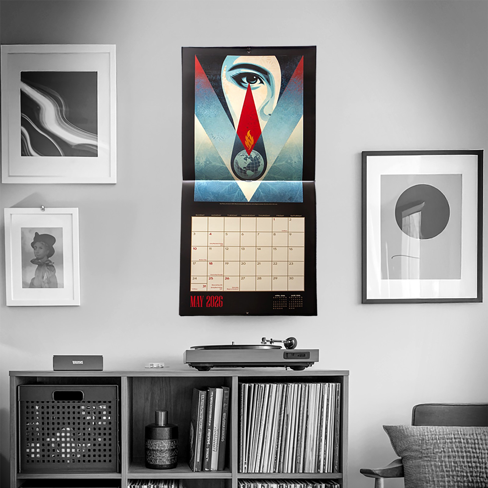 2026 wall calendar featuring eye and flame artwork, displayed above vinyl records and turntable.