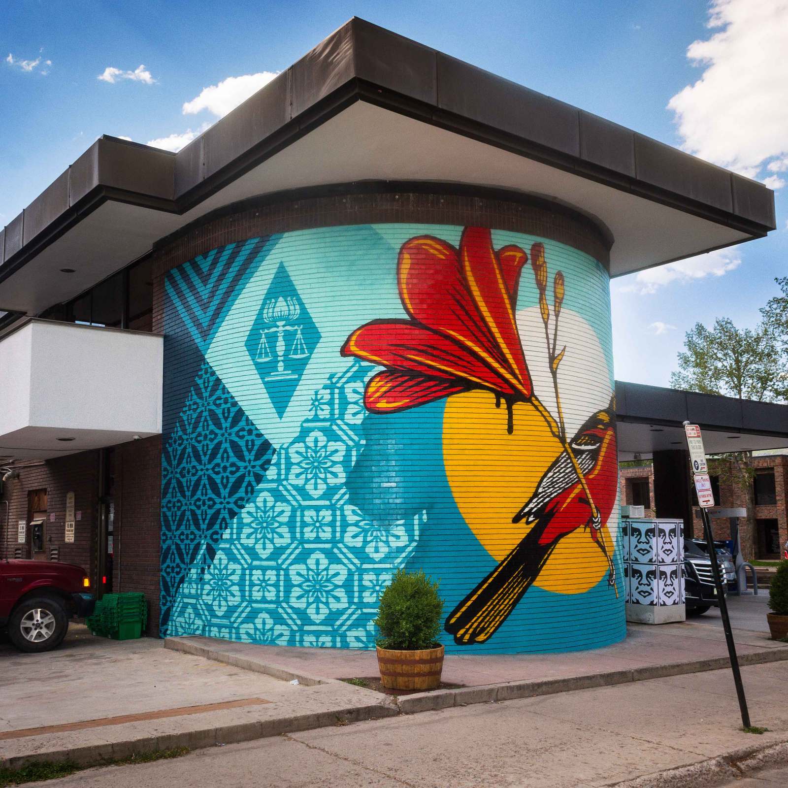 Colorful mural on brick building; bird, flower, and geometric patterns.