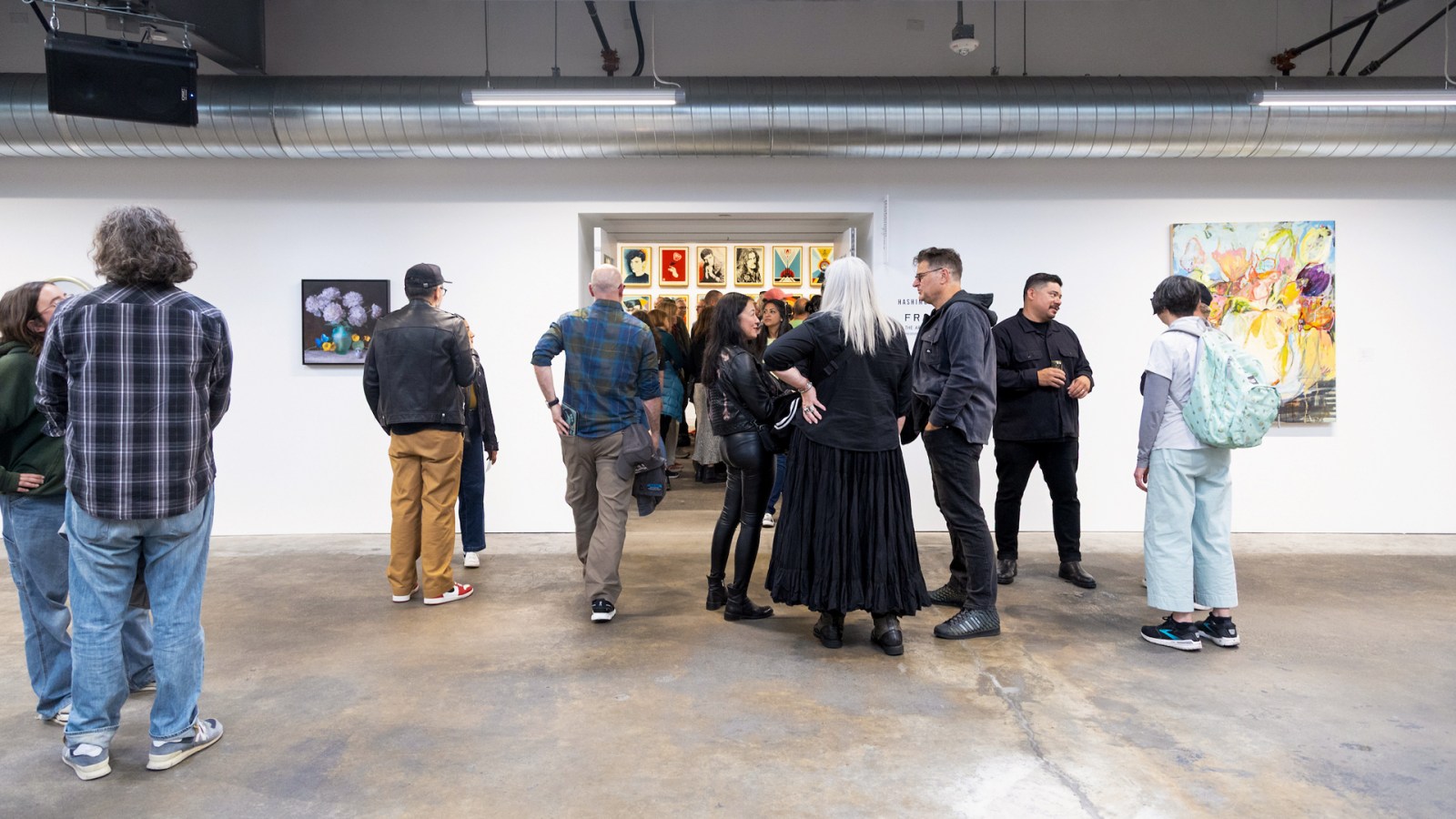Art gallery opening reception; guests mingle among displayed artwork.