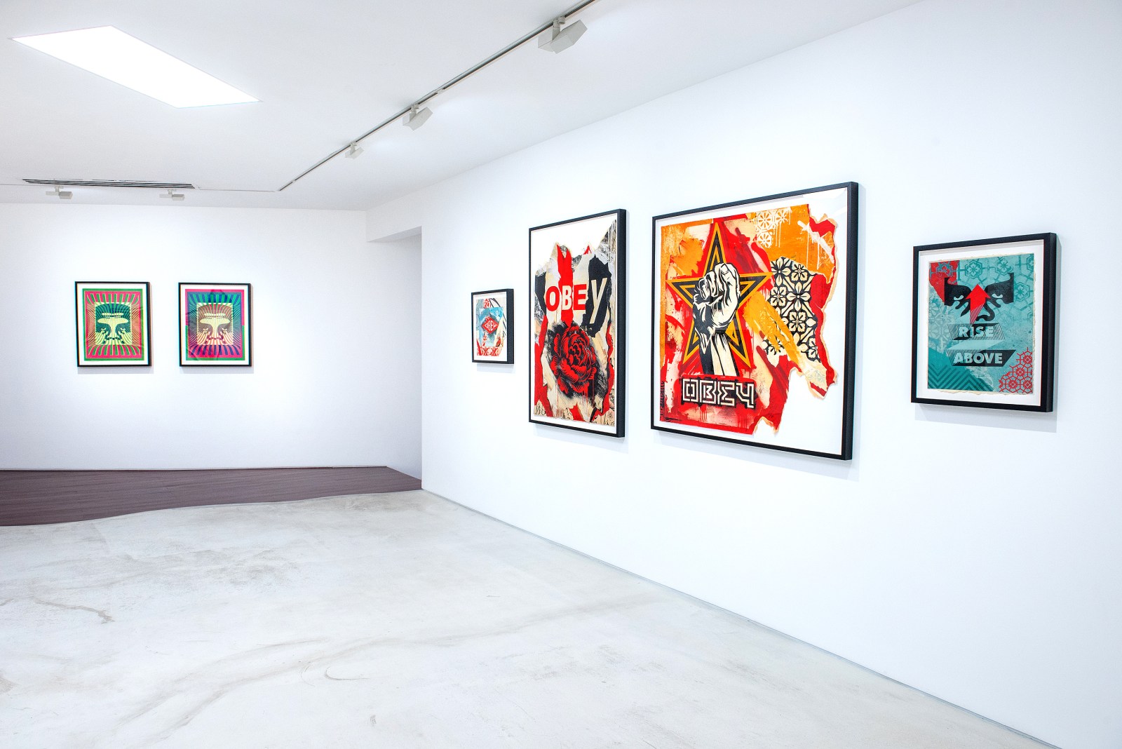 An art gallery wall displaying several pop art prints, including a large red and black print with a raised fist and the word