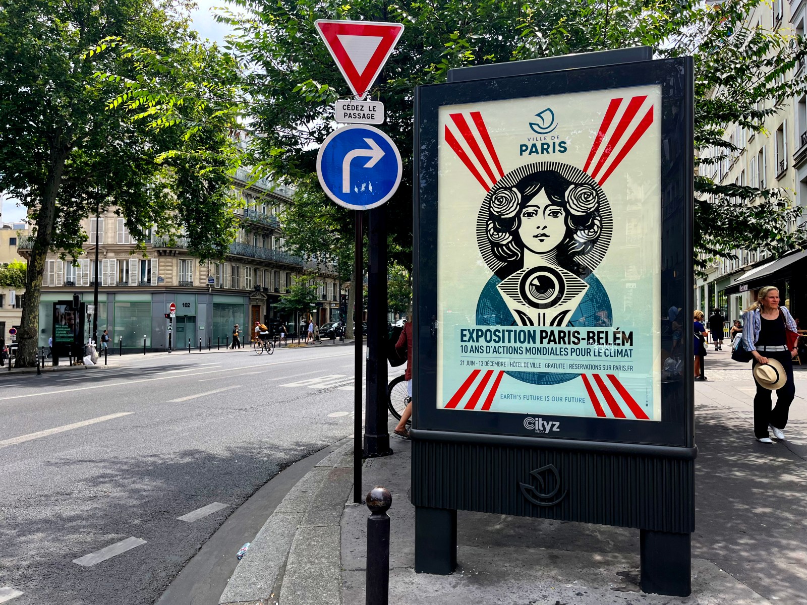 A street scene in Paris with a billboard displaying a poster for 'Exposition Paris-Belém' featuring a stylized woman and…