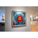 Art gallery with a large framed artwork featuring a red vinyl record design on a blue patterned background, with other…