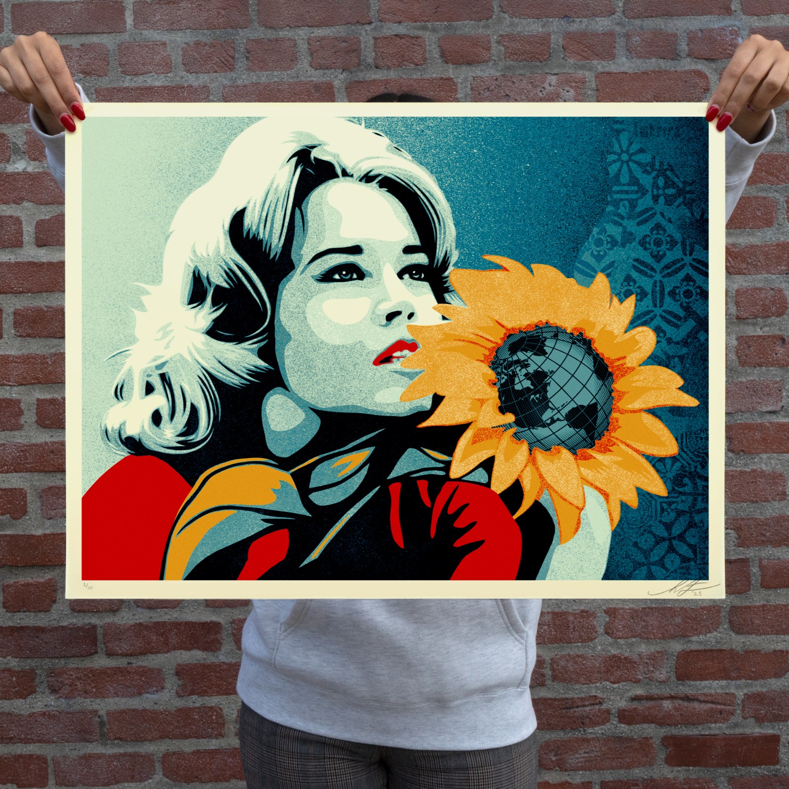 Woman holding a silkscreen print of a woman with a sunflower containing the globe.