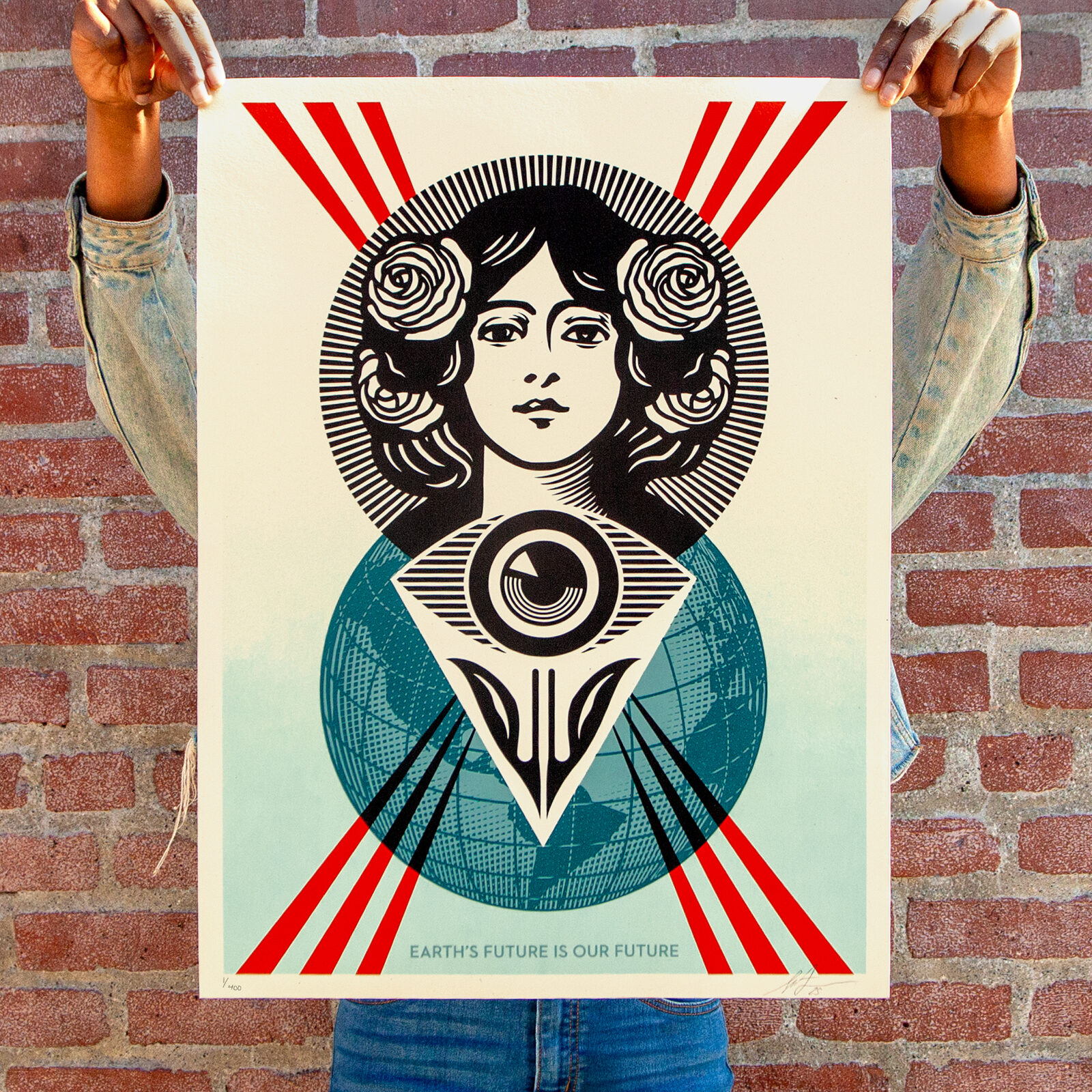A person holds a poster with a stylized woman's face, roses, an eye, and a globe, with text 'Earth's Future Is Our Future.'