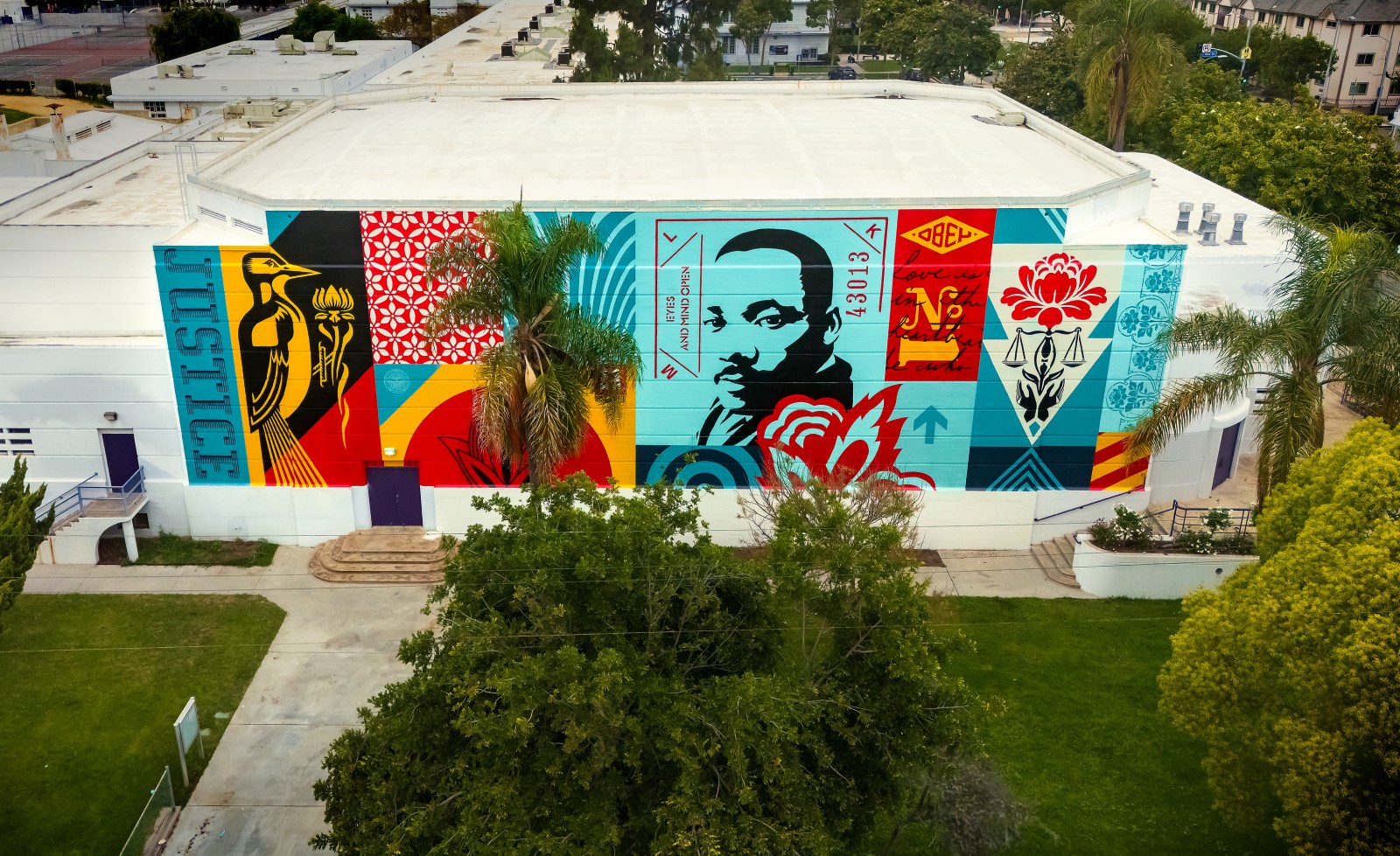 An aerial view of a vibrant mural on a building featuring a bird, Martin Luther King Jr.'s portrait, and various patterns in…